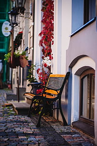 empty brown and black wooden bench beside white wall thumbnail