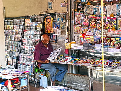 man seating on gray chair reading newspaper thumbnail
