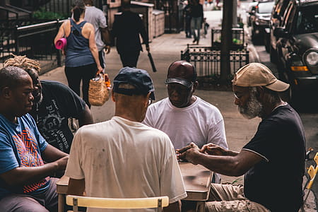 Men Sitting Beside Table on Pathway Near People Walking Beside Rail thumbnail