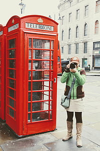 woman holding camera standing near telephone booth thumbnail