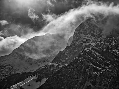 grayscale photography of mountain under white clouds thumbnail