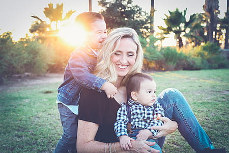 woman and two kids on green grass during golden hour thumbnail