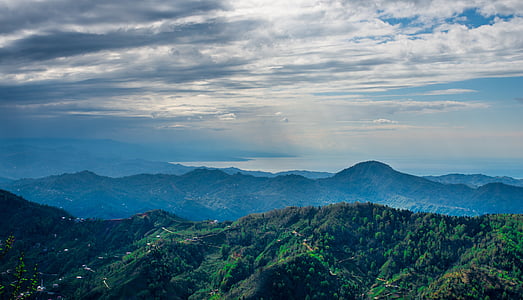 mountains covered with trees under gray clouds at daytime thumbnail