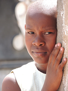 boy wearing white sleeveless shirt peeping behind concrete wall during daytime thumbnail