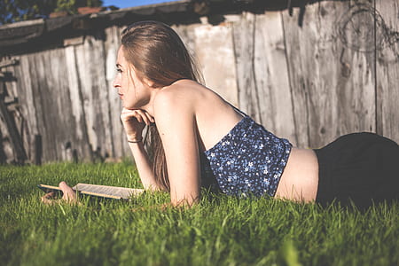 woman lying on grass reading book thumbnail