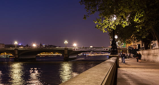 people walking on pathway beside body of water during night time thumbnail