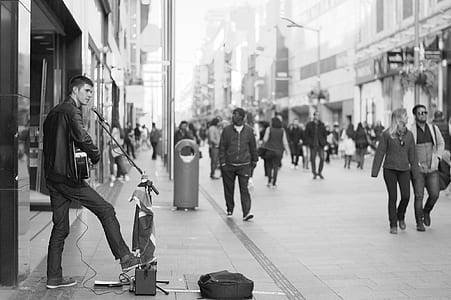 grayscale photo of man performing instrument at street thumbnail