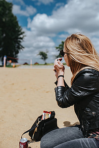 Young woman wearing a leather jacket and sunglasses on the beach thumbnail