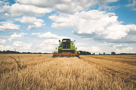 green harvester on open field under blue sky with white clouds during daytime thumbnail