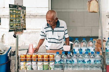 man in front assorted bottles and cans on gray food stand thumbnail