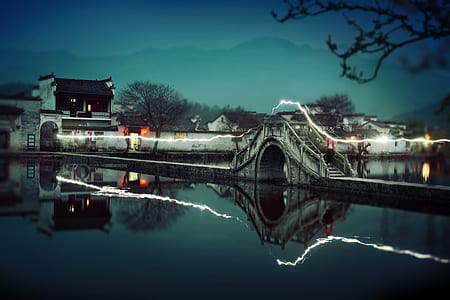 timelapse photography of bridge overlooking mountain under dark sky at night time thumbnail