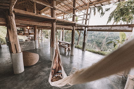 woman lying on brown hammock hanged inside house thumbnail