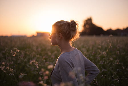 woman standing in grass field during sunset thumbnail