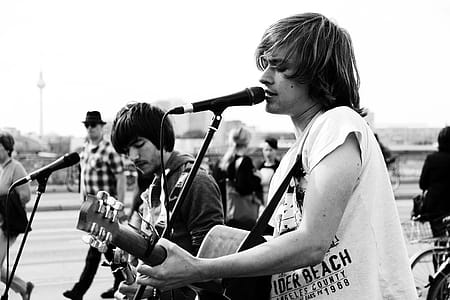 Grayscale Photo of Man Playing Singing and Playing Guitar thumbnail