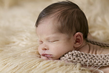 baby laying on beige bed thumbnail