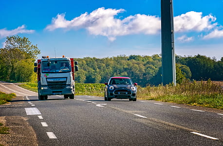 black Mini Cooper and white truck on road near tower thumbnail