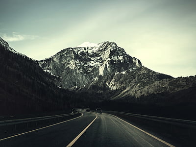 vehicles on road within mountain range during daytime thumbnail