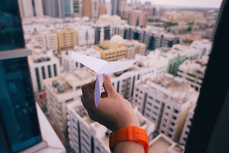 person holding white paper airplane inside room thumbnail