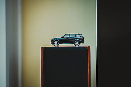 black SUV die-cast toy on brown and black furniture thumbnail