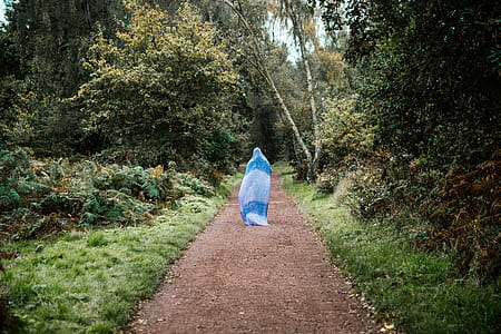 A woman walking on a forest path with her entire body covered thumbnail