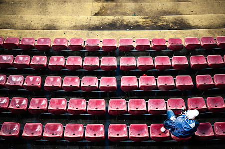 person sitting on pile of red chairs thumbnail