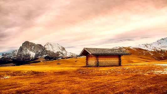 brown shed on brown soil near mountain range thumbnail