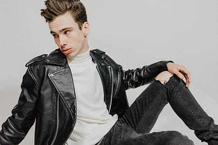 man in black leather jacket near white wall thumbnail