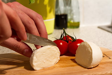 person slicing cheese beside tomatoe thumbnail