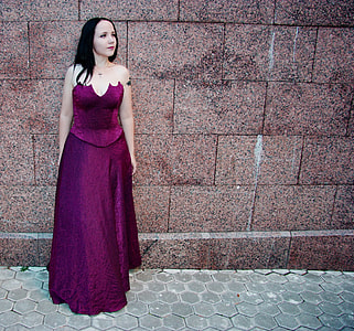 woman in red dress leaning on brown wall thumbnail