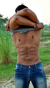 man wearing gray shirt taking off his shirt during daytime thumbnail