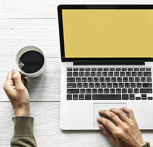 Person's Hand on Laptop and Holding Coffee thumbnail