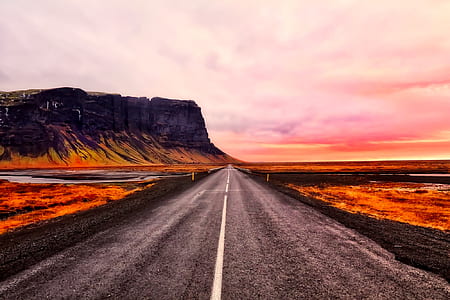 gray asphalt road near plateau under cloudy skies thumbnail
