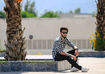 selective focus photography of white and black checkered long-sleeved shirt and black pants sitting on concrete bench thumbnail