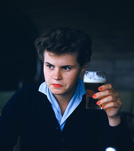 man wearing black button-up cardigan holding drinking glass filled with beer thumbnail