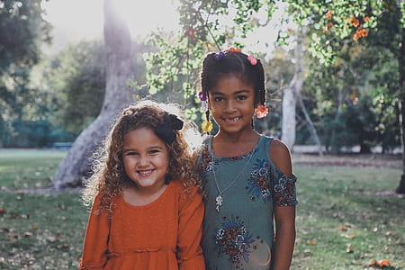 two girl standing near green leafed trees during daytime thumbnail