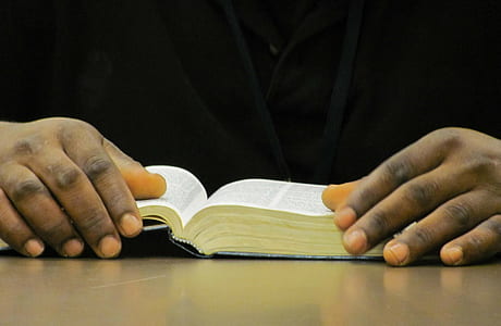 person holding book on brown wooden table thumbnail