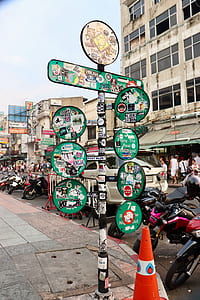 green and black road signage with stickers beside traffic cone thumbnail