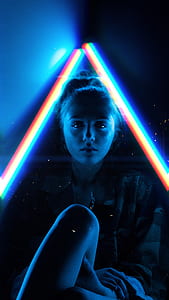 sitting woman with one knee up in between triangular LED lights thumbnail