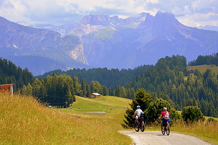 two people riding bicycle on road near mountains during daytime thumbnail