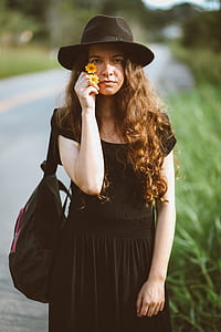 woman holding two yellow flowers standing near the road thumbnail