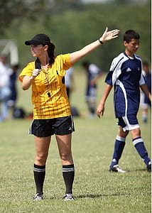 female referee rising left hand on green open field thumbnail