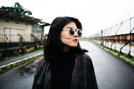 woman standing between building under white clouds during daytime thumbnail