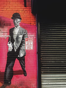 man painting on brick wall beside roller shutter thumbnail