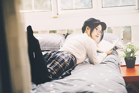 woman lying on bed while holding book thumbnail