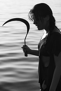 woman holding sickle near body of water thumbnail