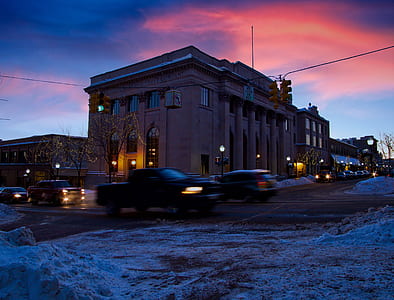 cars near brown building at night thumbnail