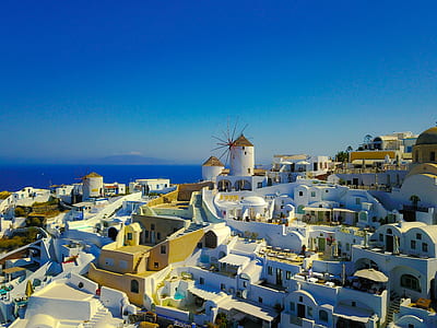 white and brown village near sea under clear blue sky thumbnail