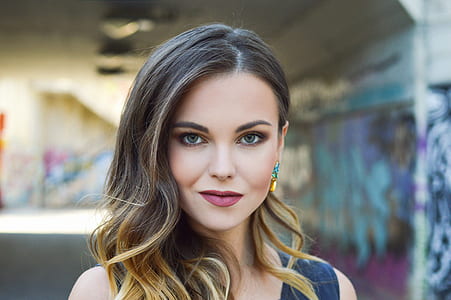 shallow focus photography of smiling woman near painted wall thumbnail