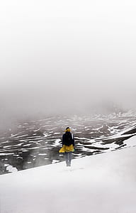 man standing on snow covered high-ground with fog thumbnail