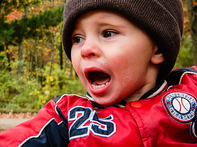 boy wearing red and black button-up jacket and brown cap during daytime thumbnail